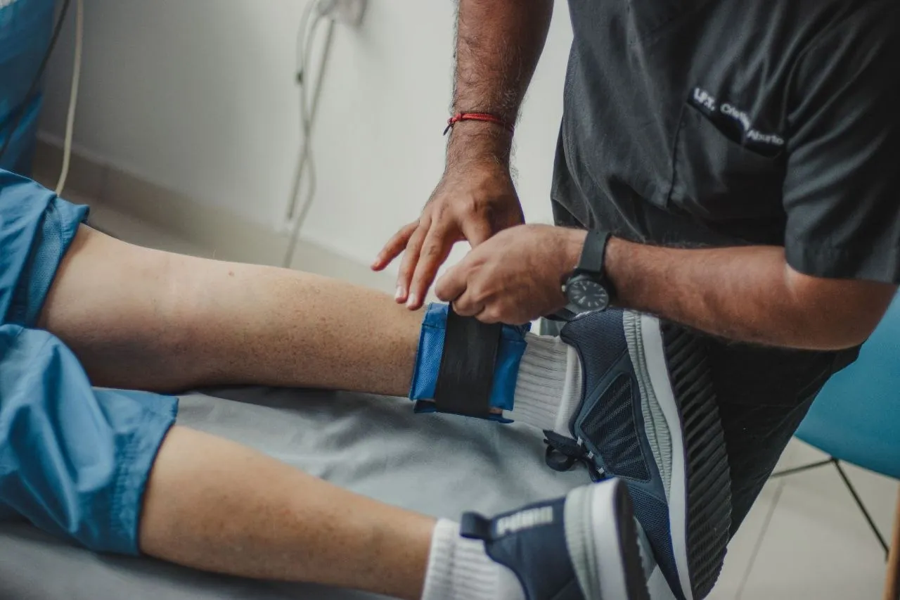 A therapist fitting a knee support on a patient