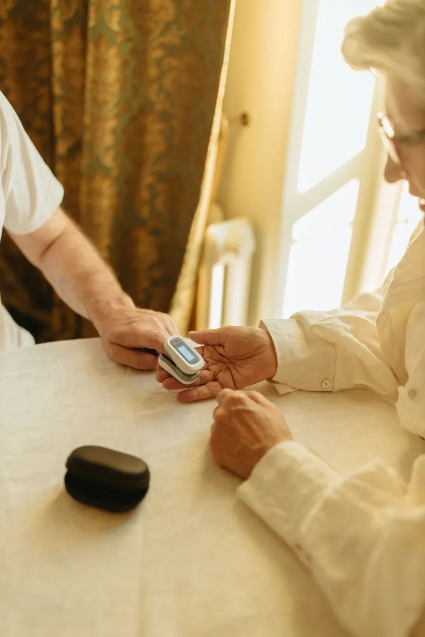 A clinician checking an older woman's pulse oxygen level at home