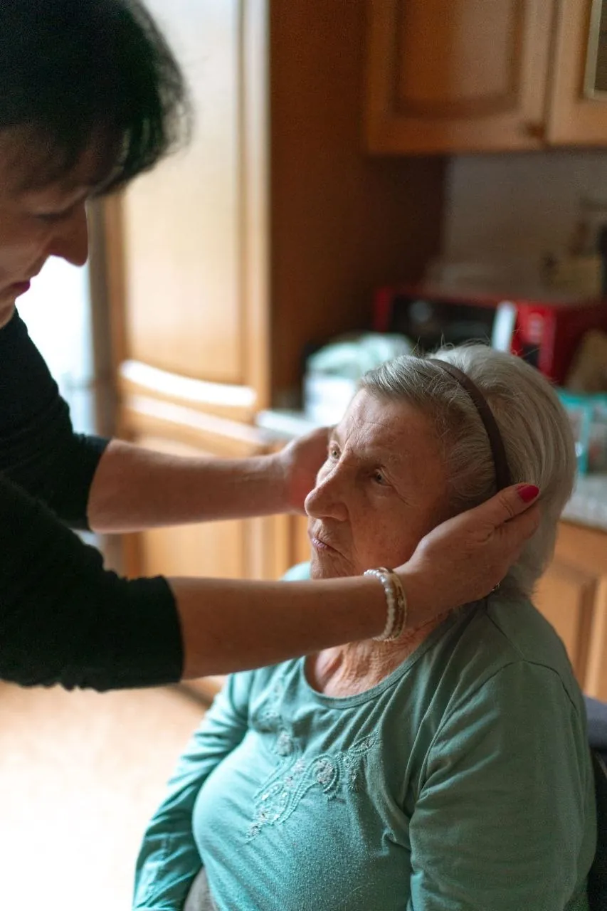 A therapist gently supporting an older woman's jaw
